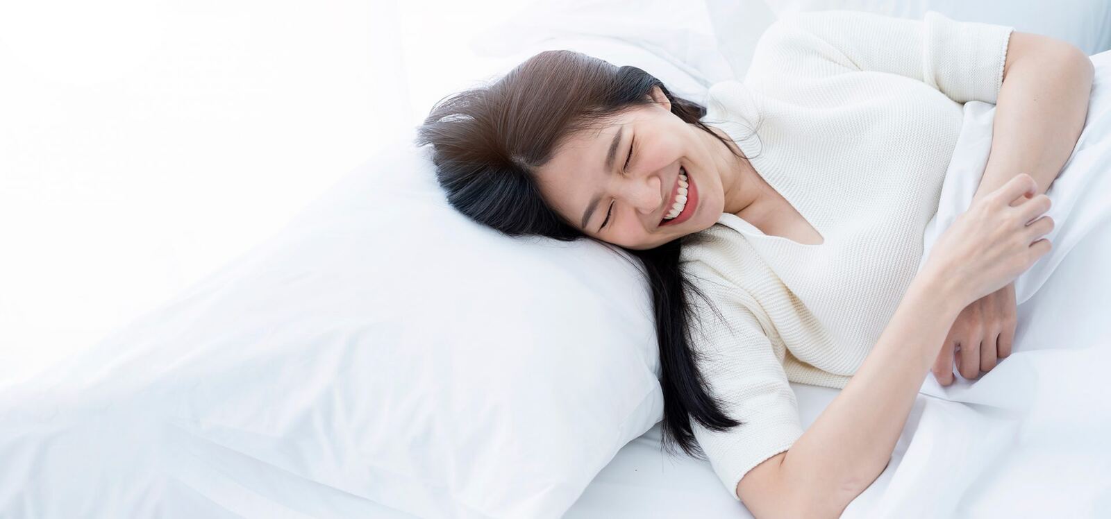 白いベッドで笑顔を見せる女性